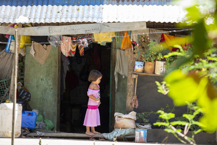 A young girl stands alone in the doorway of her home in the Philippines.