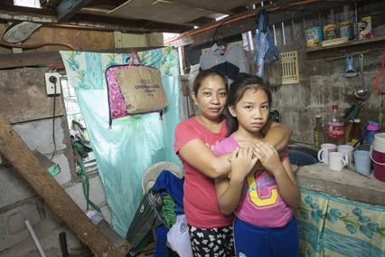 Mother and daughter standing inside hugging in Philippines.