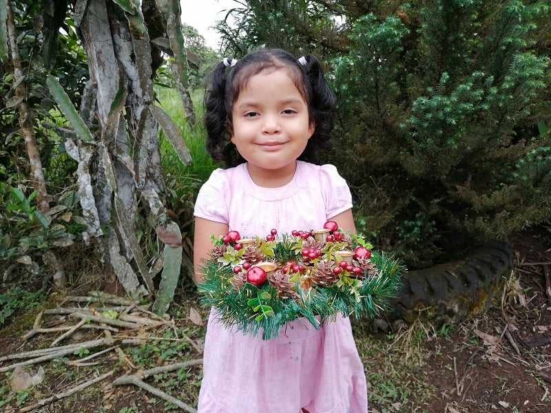 Girl holds advent wreath.