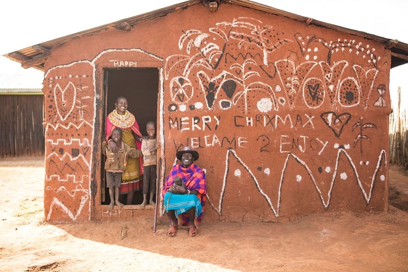 A family in Kenya standing in the doorway of their house at Christmas.