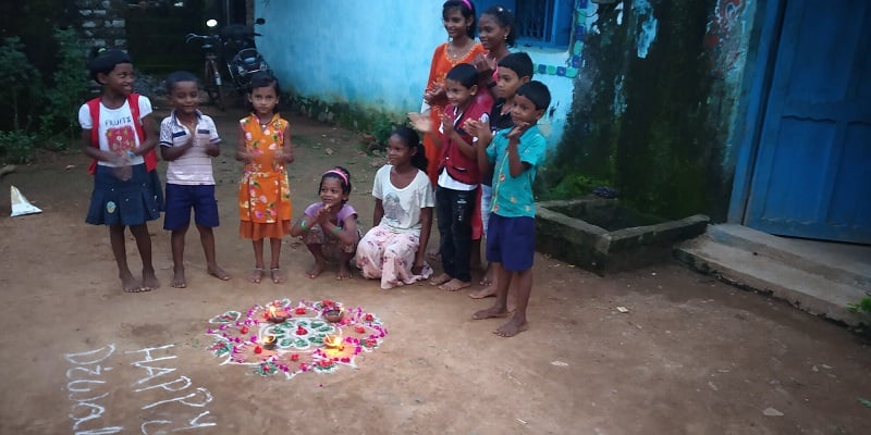 Children in India celebrate Diwali with a mandala outdoors.