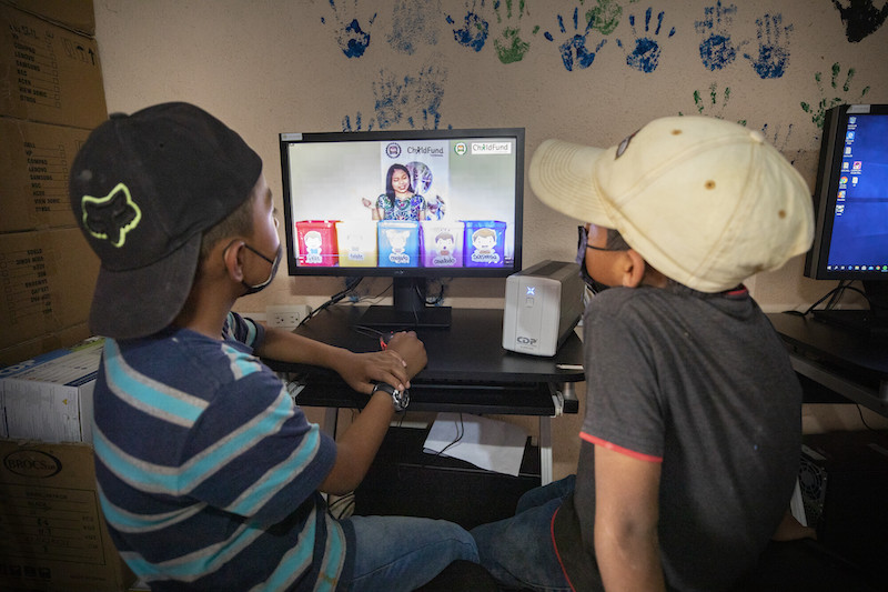 boys watch a ChildFund program on a computer monitor