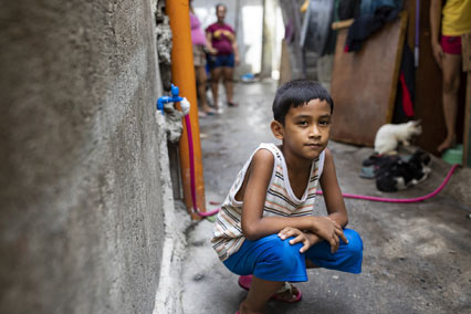 Boy in Philippines squatting in alleyway.