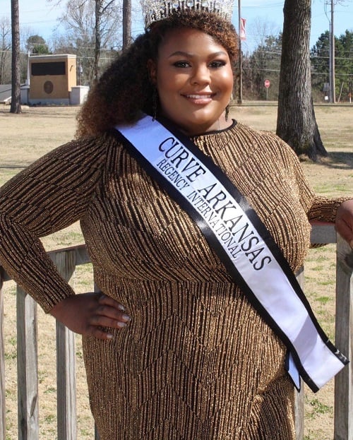 Young woman smiles wearing a crown and sash