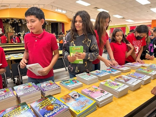 Children choose books from a table.