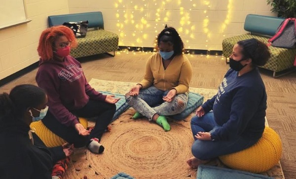 Teenagers sit on the floor in a circle, meditating.