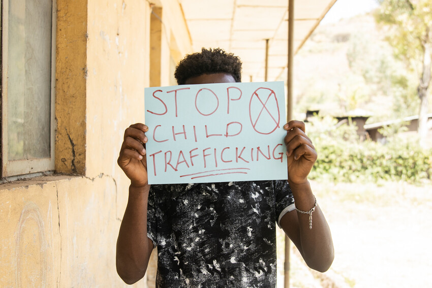 Boy in Ethiopia holds a sign up over his face.