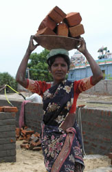 Image of an Indian woman carrying bricks to help rebuild schools