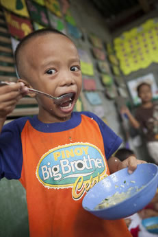 Image of a little boy eating a meal at the ChildFund Supervised Neighborhood Play center in Pili, Philippines