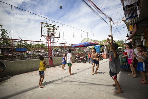 A group of kids plays basketball, crowded street in the Philippines.