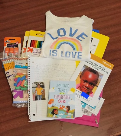 A pile of booklets and school supplies rest on a table.